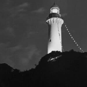Shioyasaki Lighthouse lit at twilight above a dark hill, Iwaki, Japan — minimalist lighthouse print in black and white