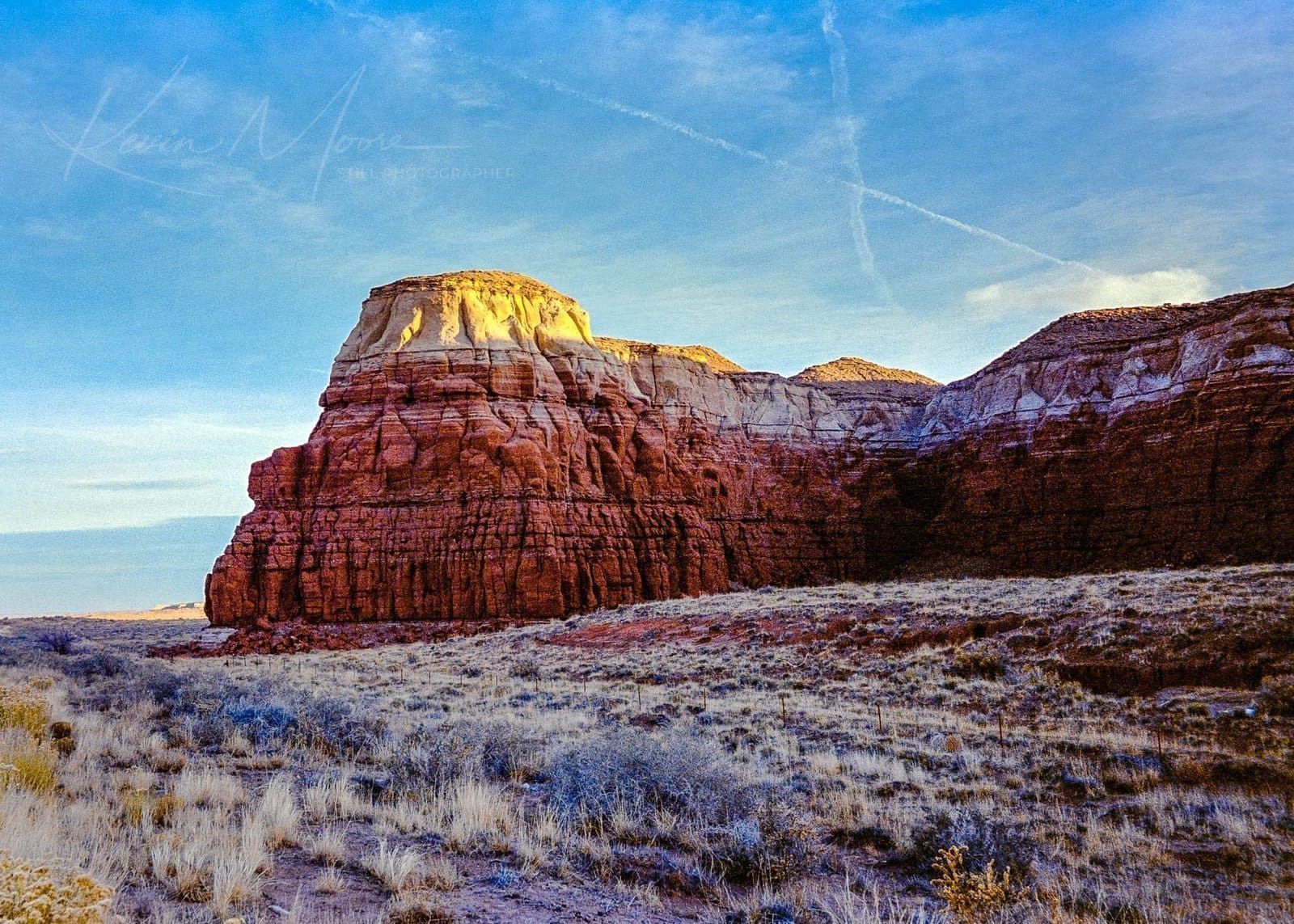 Frosted Desert Terrain: Sedimentary Rock Formations under Dusk or Dawn Light Striking desert landscape with sedimentary rock formations and frost-covered vegetation.