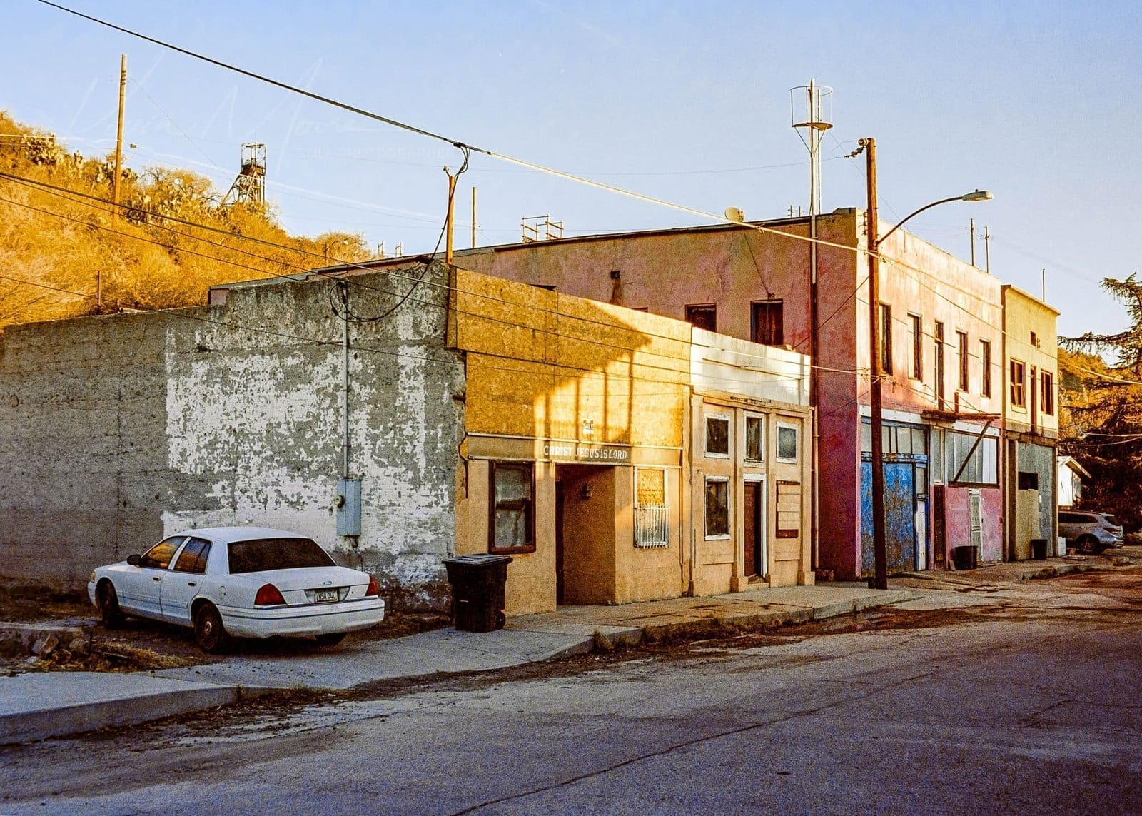 Vintage car parked on a neglected, desolate street at dusk.
