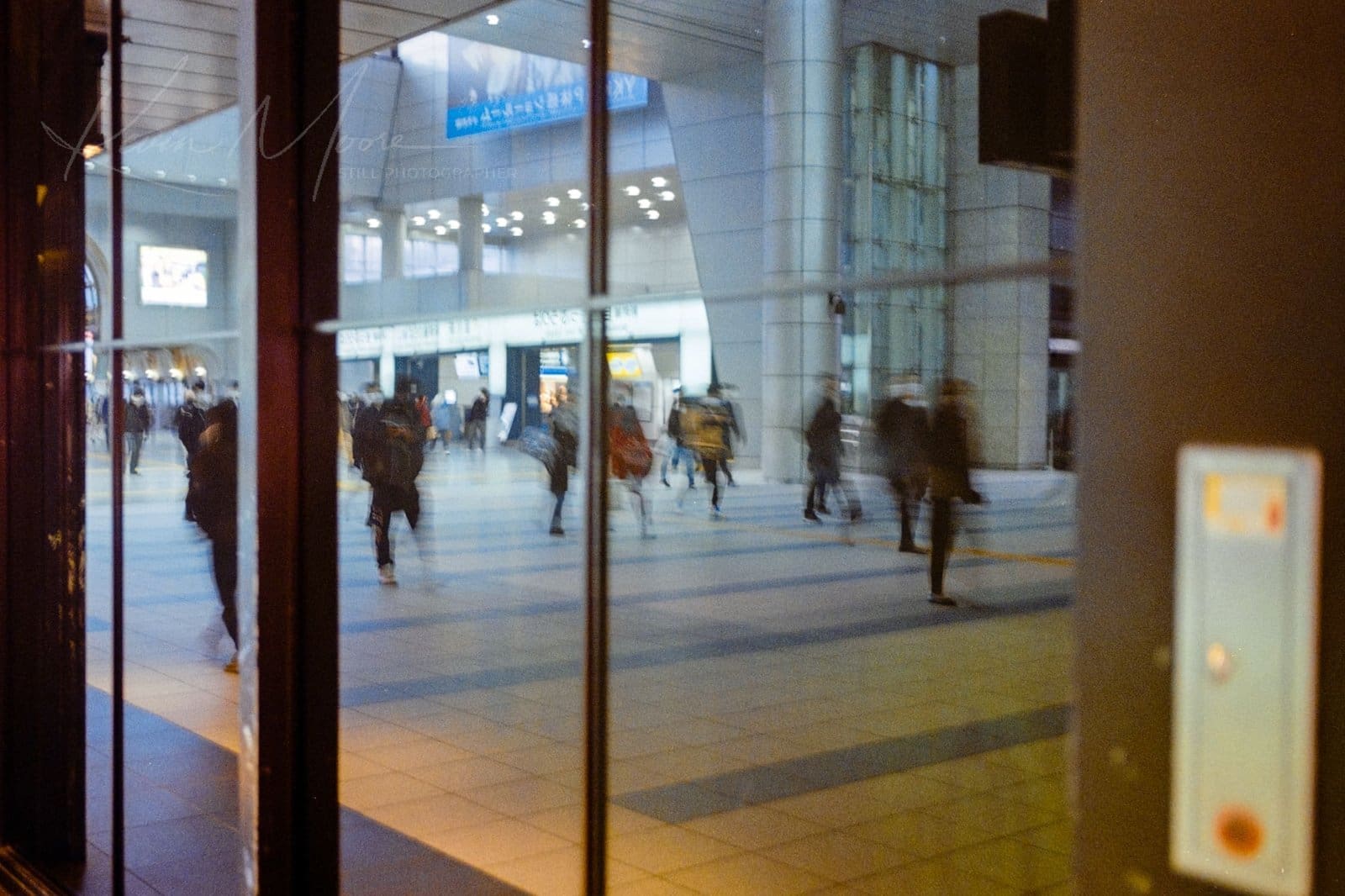 Bustling train station interior with blurred crowd in motion and modern architecture.