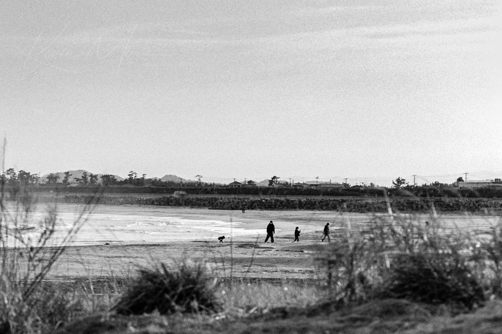 Timeless black and white beach scene with family and reflective sand.