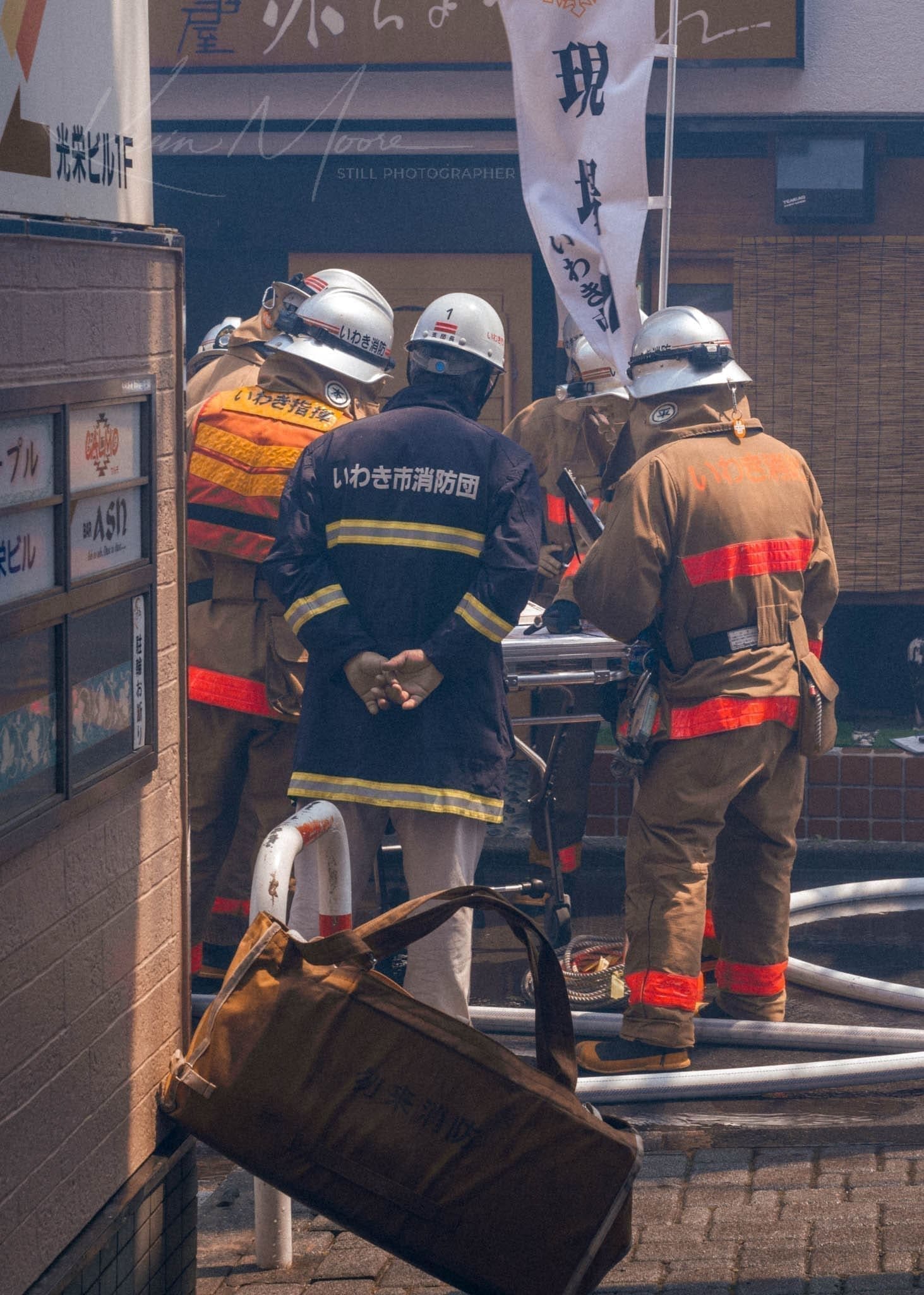 Japanese firefighters in action, wearing protective gear and assessing the situation.