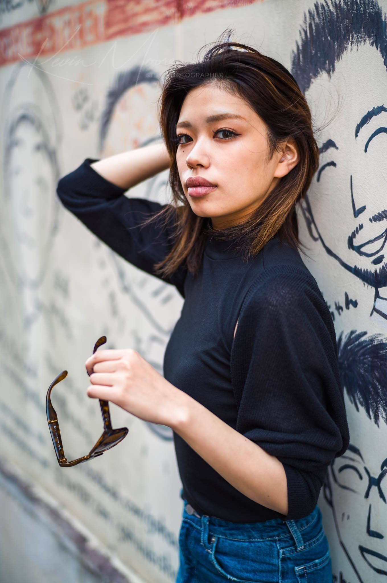 Young woman in jeans posing by artistic mural.