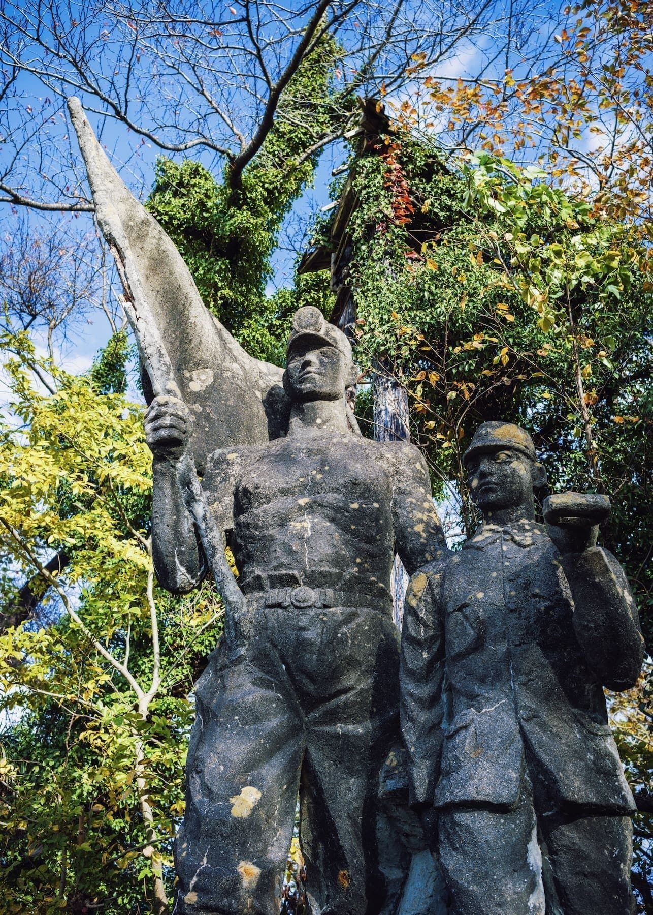 Historical soldier statues in autumn park setting.