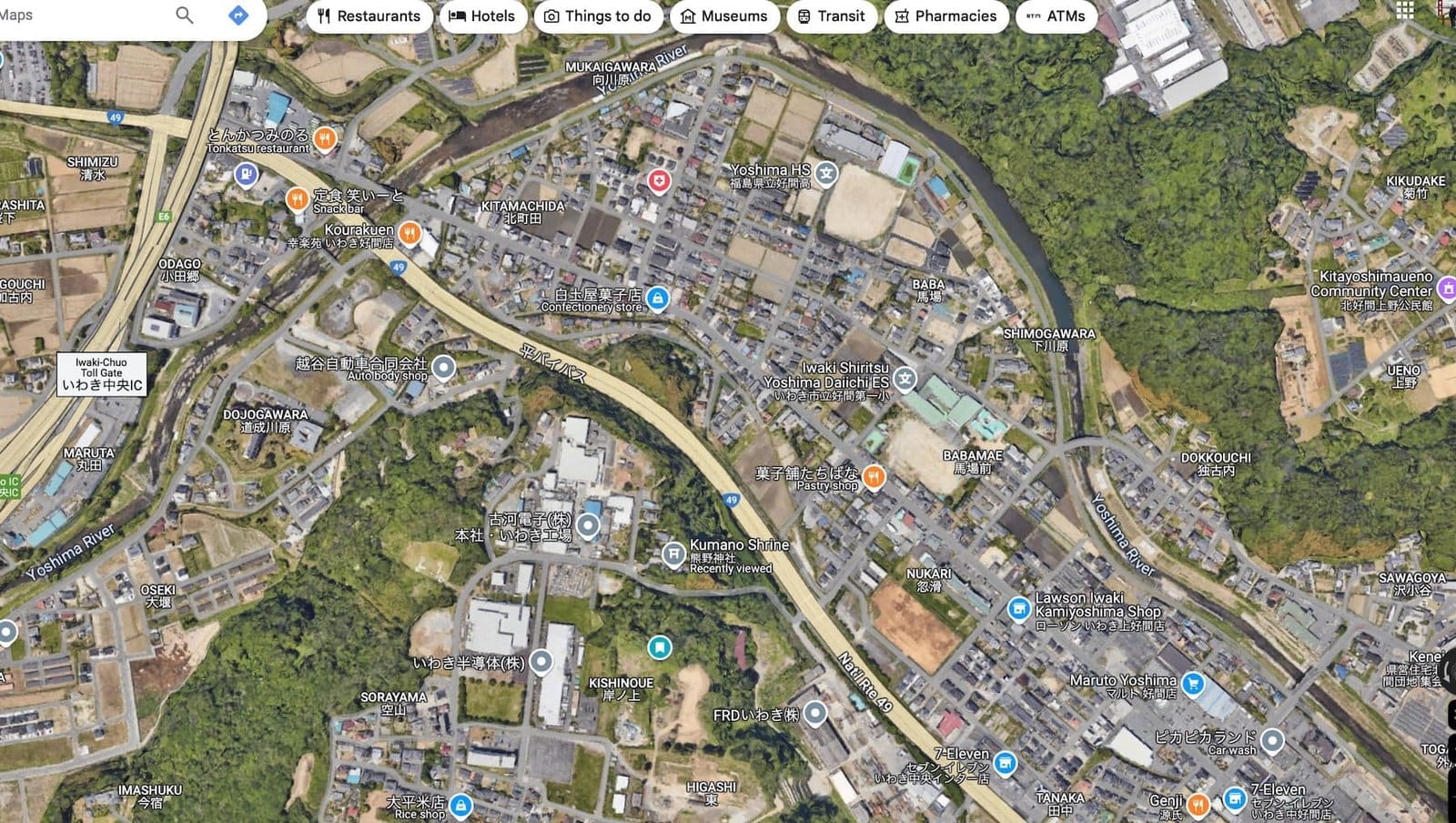 Aerial view of suburban Yoshima with homes, green spaces, and river.