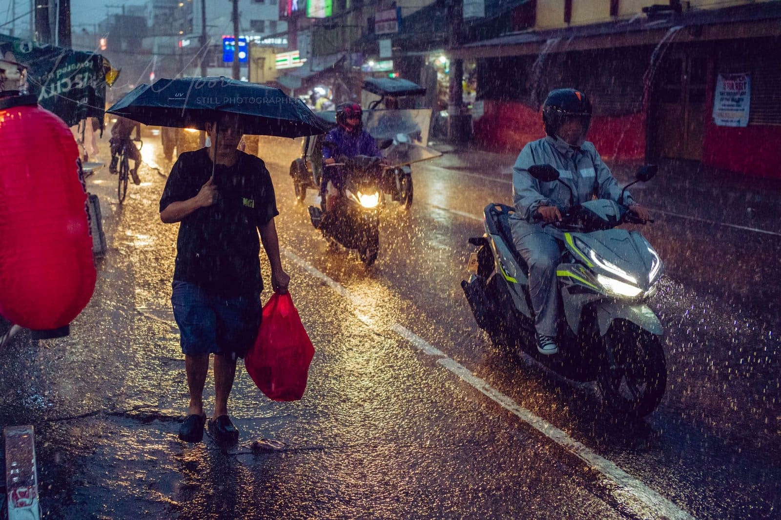Urban Resilience: Navigating a Rainy Philippines Cityscape at Dusk Rain-soaked Philippines city street with pedestrians and motorcyclists at dusk.